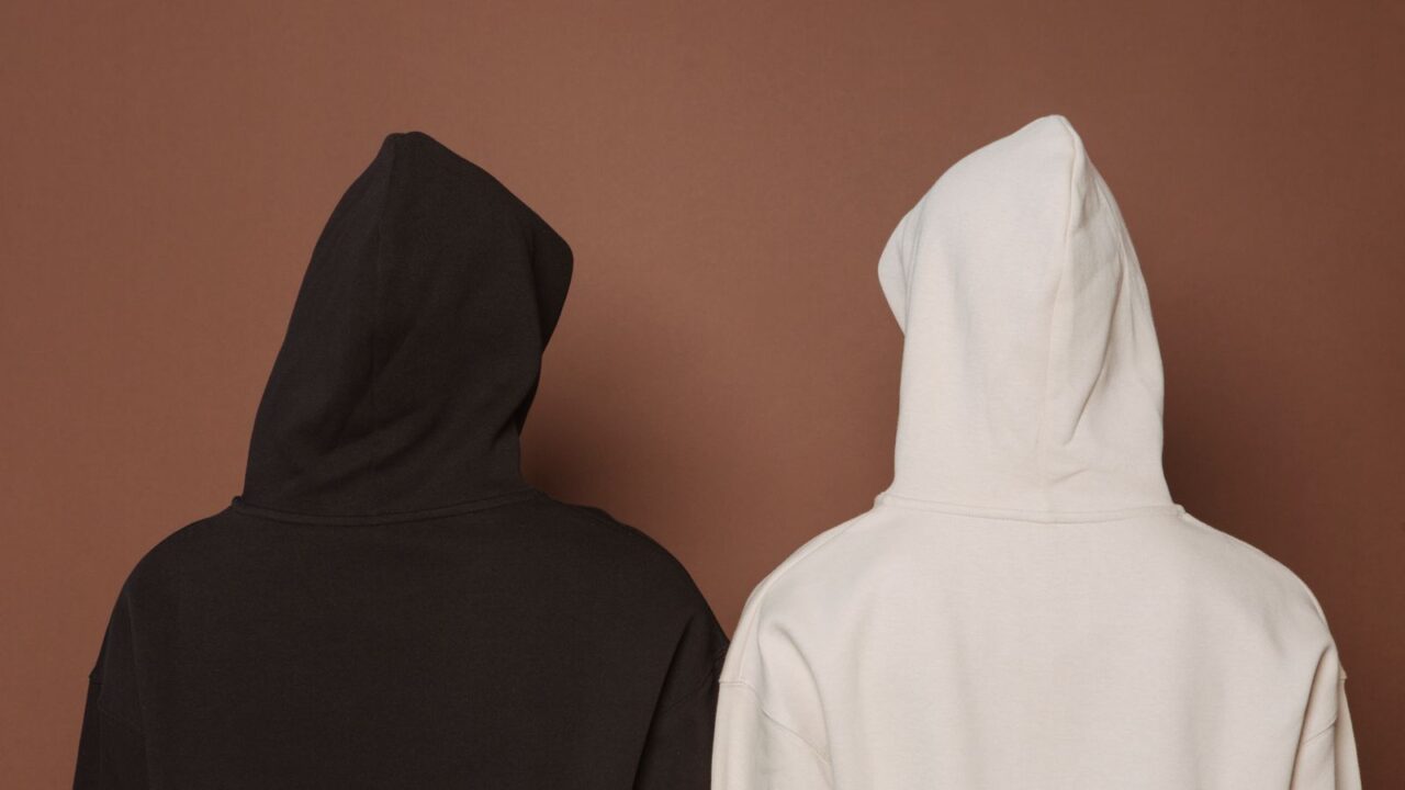 黒と生成りのオーバーサイズフーディを着た2人の後ろ姿。Fear of Godのくすんだトーンとオーバーサイズシルエットという世界観のイメージ