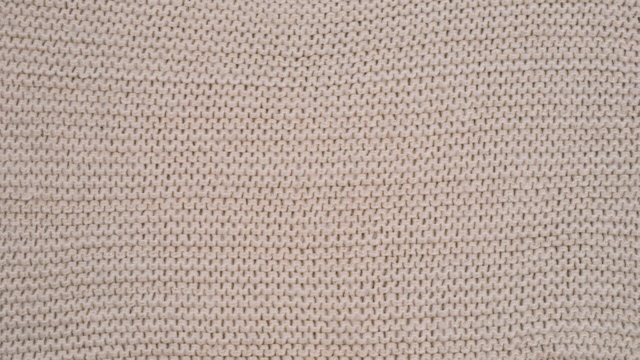 ベージュのニット生地の精緻なテクスチャー(CFCLのコンピューテーショナルニットの世界観イメージ)