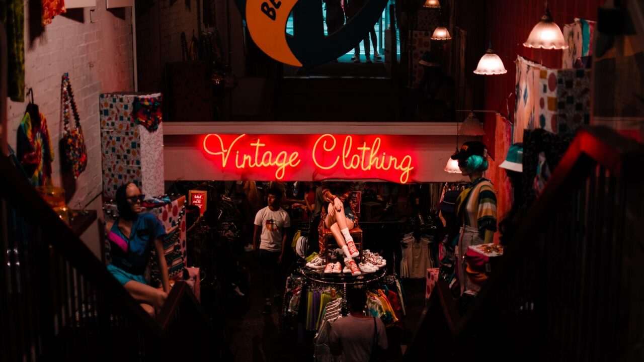 ネオンサインの「Vintage Clothing」が灯る古着店の店内を見下ろした風景