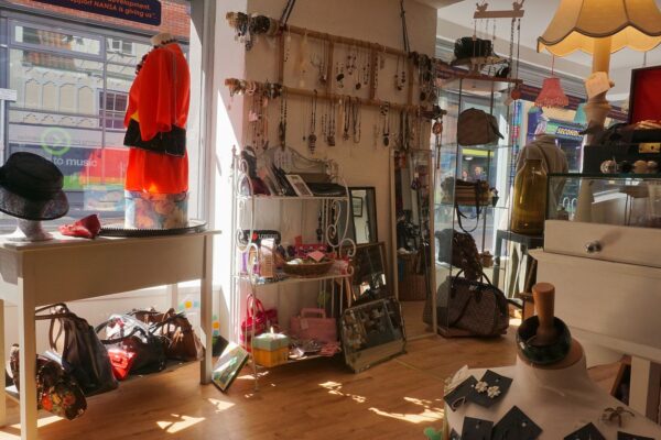 洋服とバッグ、帽子や小物が明るい照明の下に並ぶ古着店の店内（新潟の古着屋ガイドのイメージ）