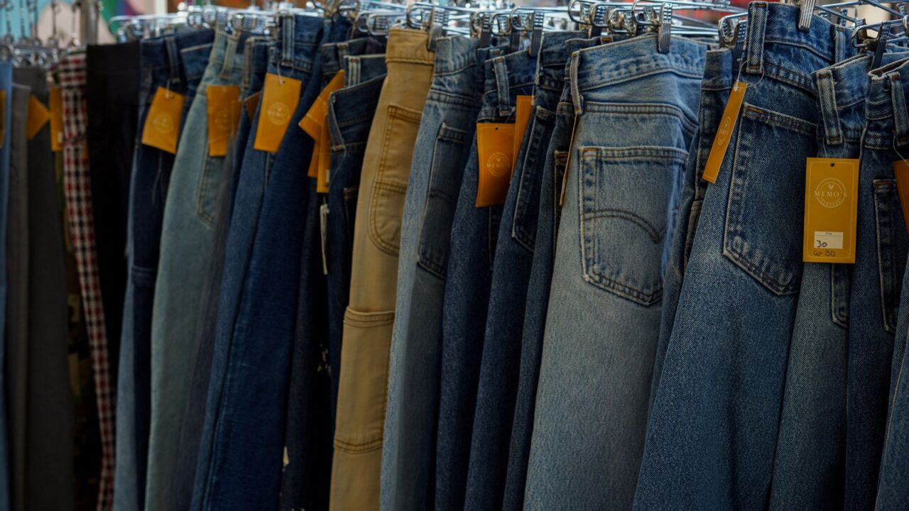 タグ付きのデニムパンツがずらりと並ぶ古着店の店内（岡山市の古着屋ガイドのイメージ）
